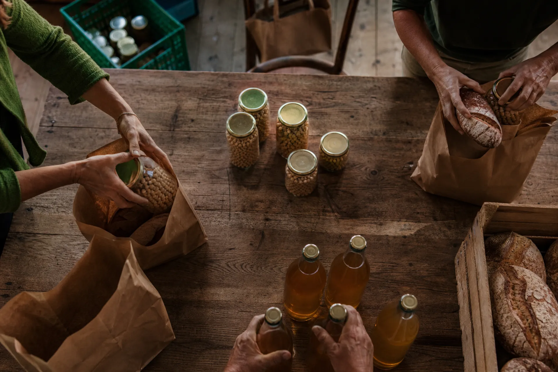 Vue de dessus de bénévoles préparant des sacs d'épicerie et de pain bio sur une grande table en bois.
